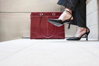Businesswoman's feet in high heeled shoes and her purse.