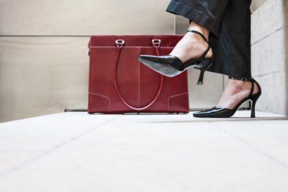 Businesswoman's feet in high heeled shoes and her purse.