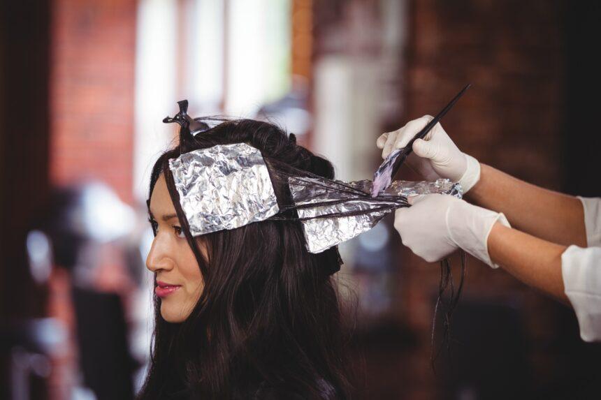 Hairdresser dyeing hair of her client