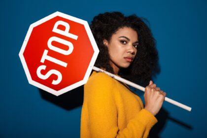 Displeased african woman holding stop symbol sign.