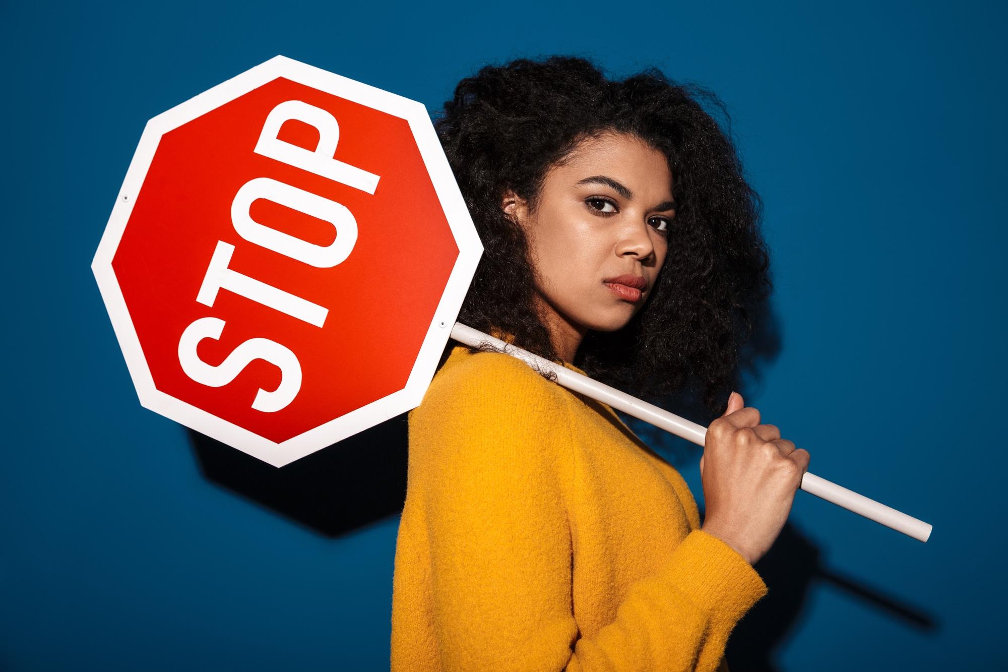Displeased african woman holding stop symbol sign.