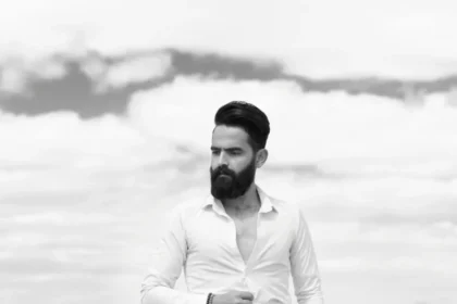 Portrait of an adult man smiling in front of a metal shutter.