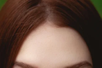 A captivating close-up of a woman's brown eyes partially obscured by foliage.