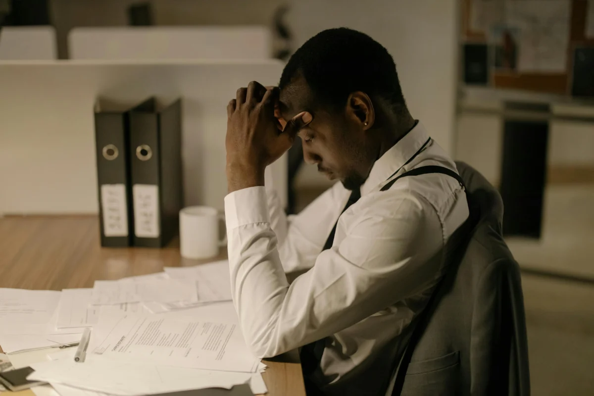An adult man in an office is concentrating on documents, reflecting stress and focus in a work environment.