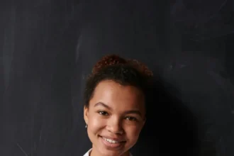 Portrait of a smiling woman in a white shirt posing confidently indoors.