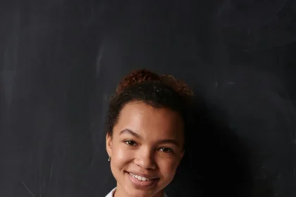 Portrait of a smiling woman in a white shirt posing confidently indoors.