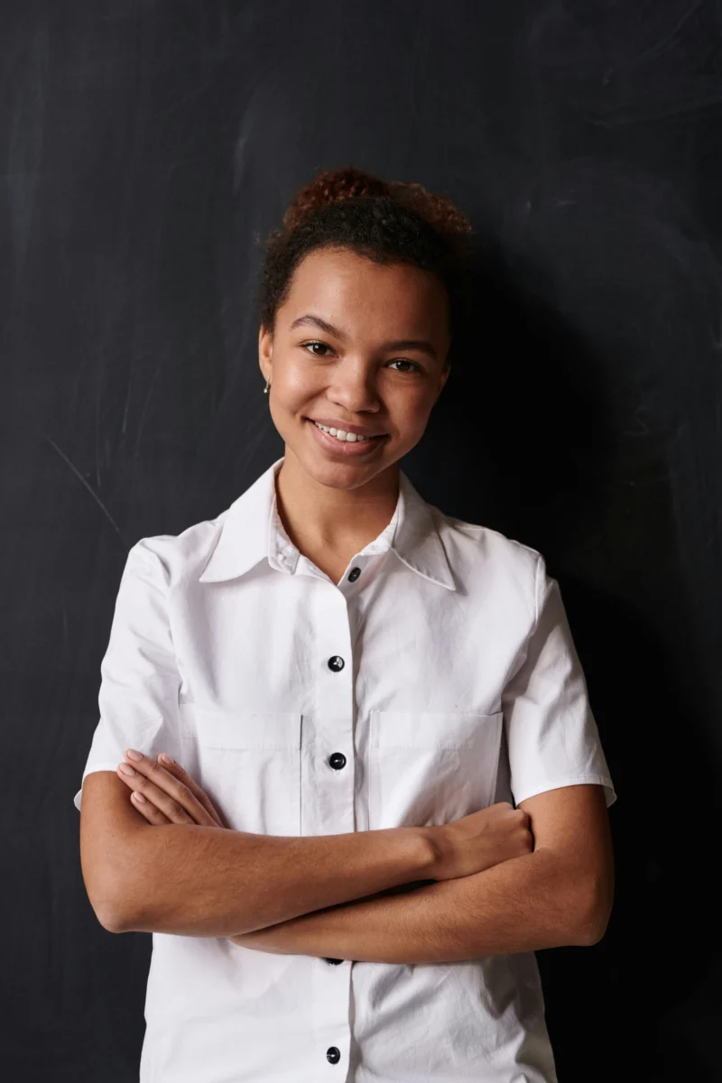 Portrait of a smiling woman in a white shirt posing confidently indoors.