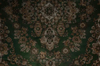 A striking visual of flowers burning on a concrete floor with a vintage carpet backdrop.