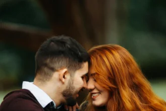 Happy couple sitting outdoors, embracing and sharing a joyful moment.