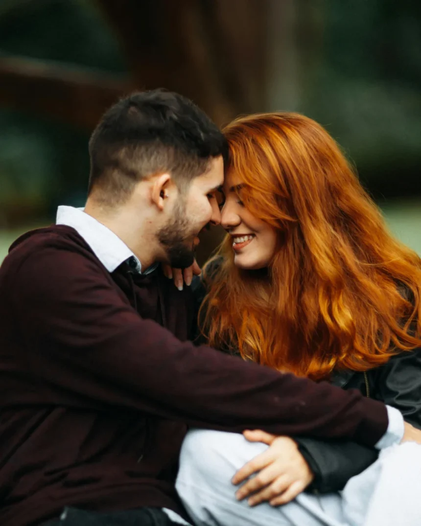 Happy couple sitting outdoors, embracing and sharing a joyful moment.