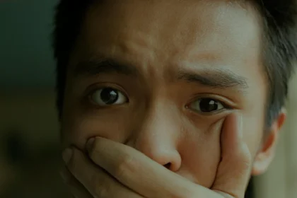 A young man with a distressed expression, covering his mouth.