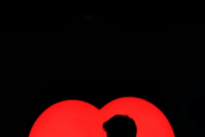 Silhouette of a loving couple embracing against a vibrant heart backdrop.