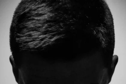 A dramatic black and white portrait of a shirtless man in a pensive pose, conveying deep thought.