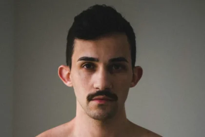 Portrait of a shirtless man with a moustache, highlighting masculinity and strength.
