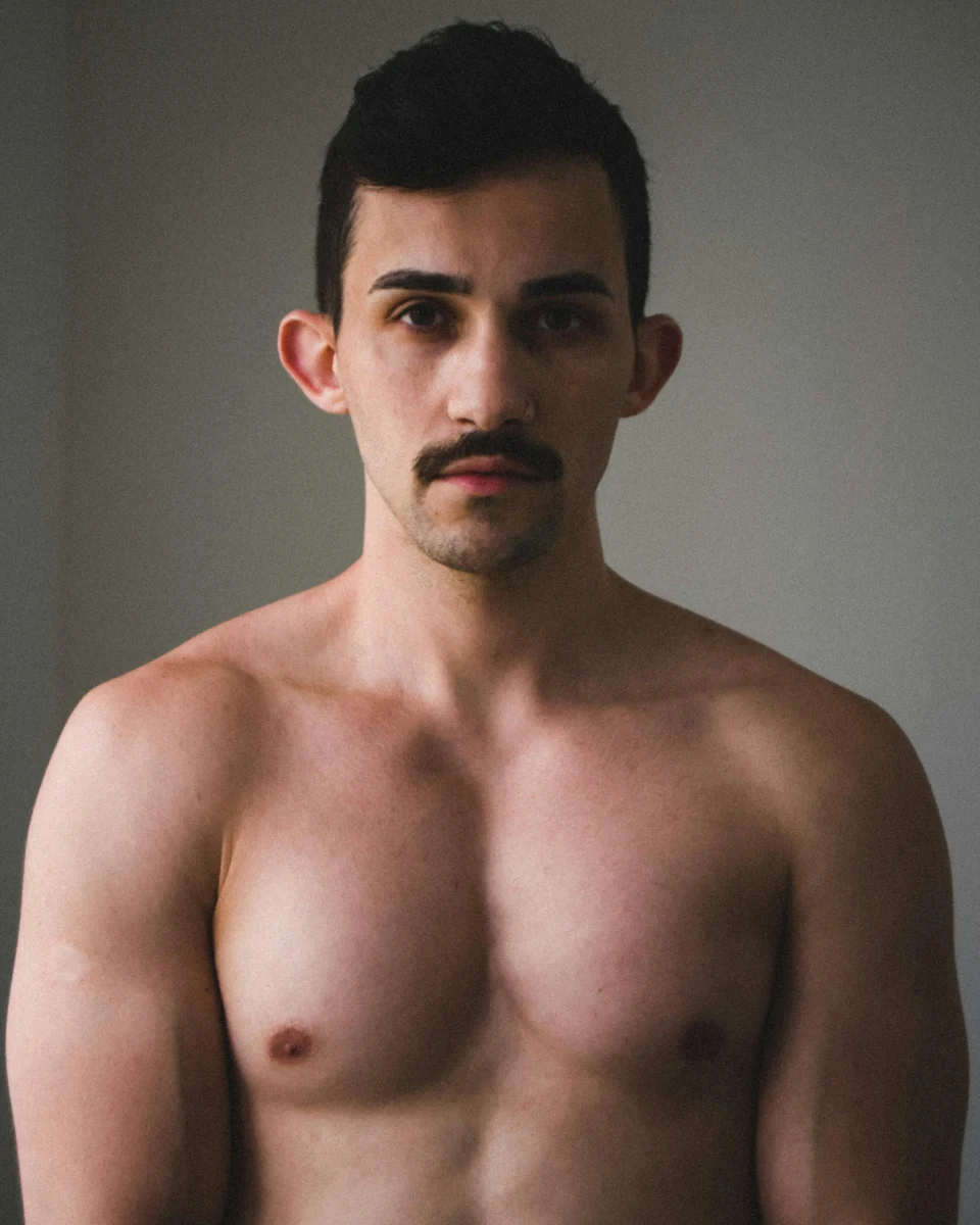 Portrait of a shirtless man with a moustache, highlighting masculinity and strength.