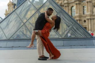 Couple in love embraces near the iconic Louvre Pyramid in Paris. Modern romance in a historical setting.