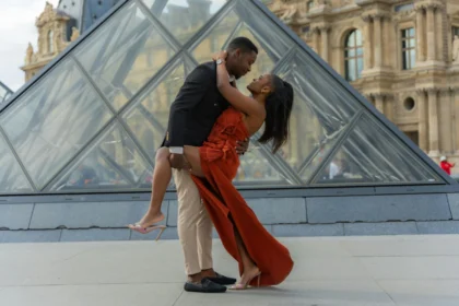 Couple in love embraces near the iconic Louvre Pyramid in Paris. Modern romance in a historical setting.