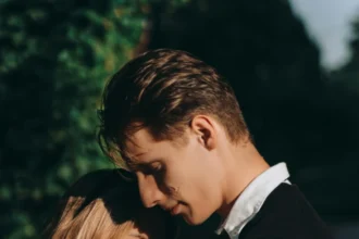 A romantic couple embracing outdoors, sharing a tender moment with a red rose.