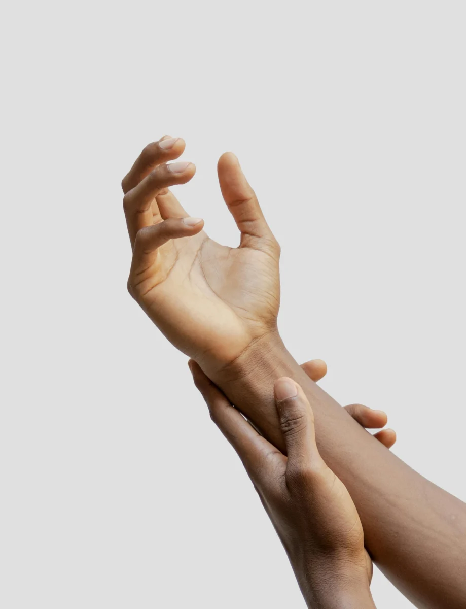 A close-up of two hands expressing connection and affection on a neutral background.