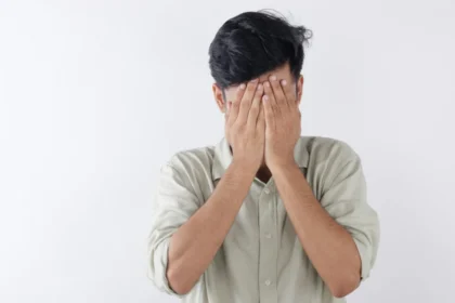 A man covering his face with hands, expressing feelings of stress and emotional struggle.